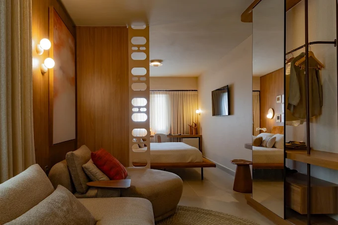 Suíte com estar integrado, madeira e luz acolhedora